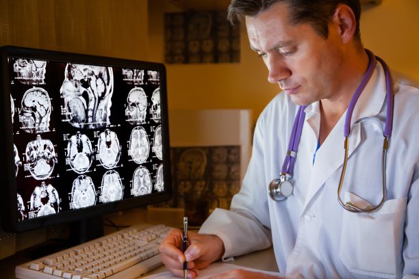 workers' compensation doctor looking at brain MRI images on a screen